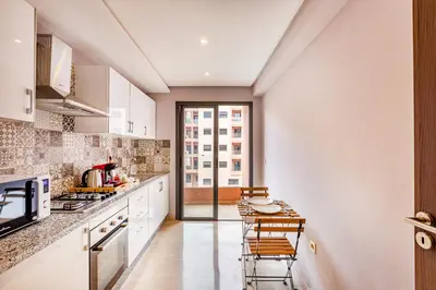 a kitchen with white cabinets and a table with chairs at Résidence jnan ali 4 Marrakech in Marrakech