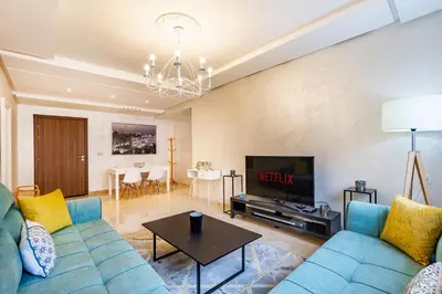 a living room with a blue couch and a tv at Résidence jnan ali 4 Marrakech in Marrakech