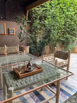 a glass table and chairs in a patio at Vibrant Modern House, 20 Min from Gueliz & Airport in Marrakech