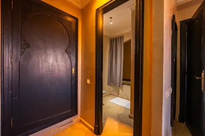 a hallway with a black door and a bathroom at River Palm, bel appartement 2 ch Piscine résidence in Marrakech