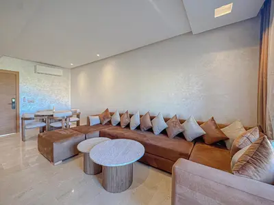 a living room with a brown couch and a table at Prestigia Argan 2Ch Piscine et Parking 6pax in Marrakech