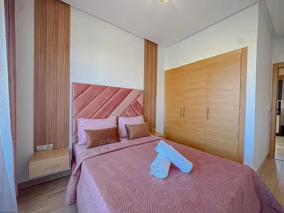 a bedroom with a pink bed with blue slippers on it at Prestigia Argan 2Ch Piscine et Parking 6pax in Marrakech