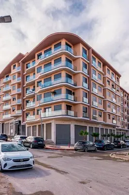a large apartment building with cars parked in a parking lot at Quiet & Secure Apt - Fast WiFi - Central Area in Marrakech