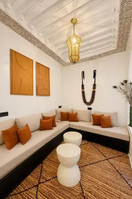 a living room with a long white couch with orange pillows at Riad chic Suite élégante au coeur de Marrakech in Marrakech