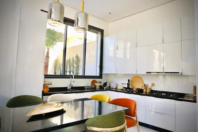 a kitchen with white cabinets and a glass table at Luxury Villa Hedi in Marrakech