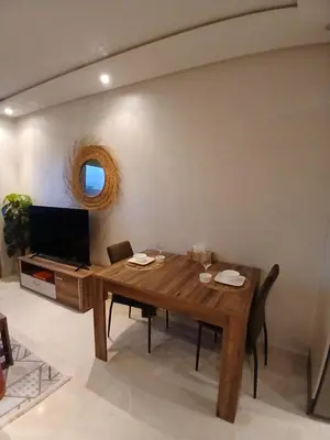 a dining room with a wooden table and a television at Studio meublé Guéliz in Marrakech