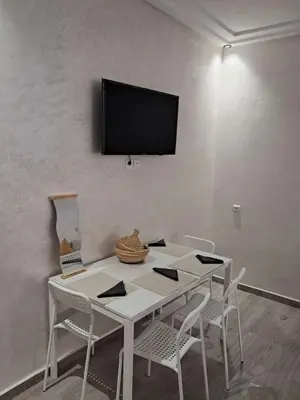 a white table with chairs and a television on a wall at comfortable stay in Marrakesh in Marrakech