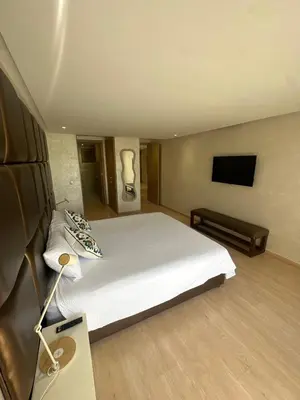 a bedroom with a white bed and a flat screen tv at Marrakech village -2 chambres jardin avec jacuzzi in Marrakech
