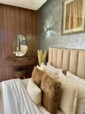 a bedroom with a bed with white sheets and furry pillows at Appartement luxe avec piscine in Marrakech