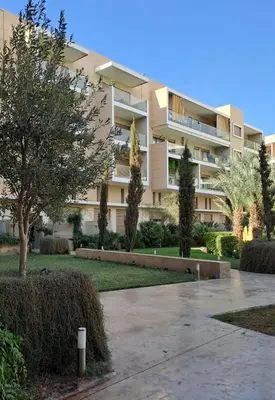 a large apartment building with a park in front of it at Appartement luxe avec piscine in Marrakech