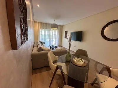 a living room with a table and a couch at Prestigia Jade Beautiful Apartment Marrakesh in Marrakech