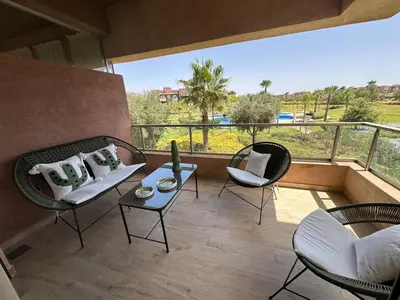 a balcony with chairs and a table with a view at Prestigia Jade Beautiful Apartment Marrakesh in Marrakech