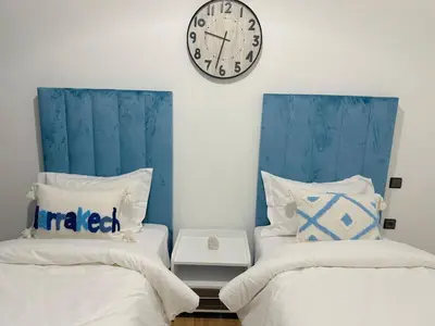 a bedroom with two beds and a clock on the wall at Marrakech Cosy appartement 2 chambres - Confort in Marrakech