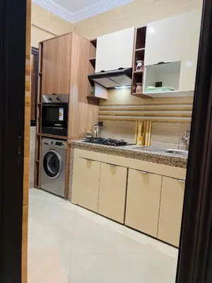 a kitchen with wooden cabinets and a washer and dryer at Marrakech Cosy appartement 2 chambres - Confort in Marrakech