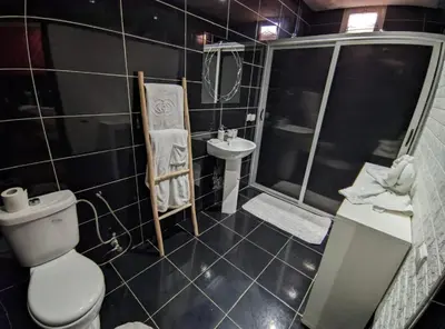 a black tiled bathroom with a toilet and a sink at Villa Riad Dar Sukar in Marrakech