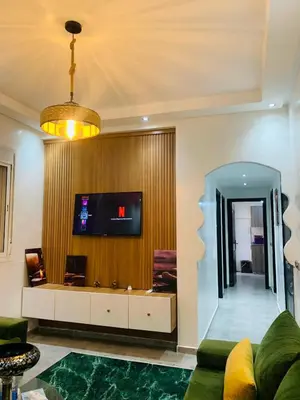 a living room with a couch and a tv on a wall at appartement lumineux parfait Cosy prêt de Guéliz in Marrakech