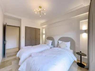 two beds in a bedroom with white walls and a chandelier at Modern & Luxurious Apartment, Terrace with panoramic view of Gueliz in Marrakech