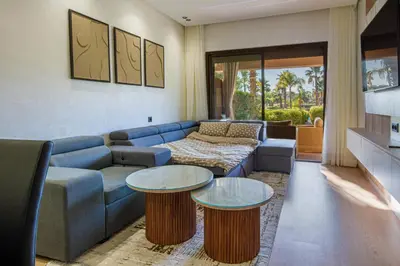 a living room with a blue couch and two tables at Marrakech golf Prestigia Jade in Marrakech