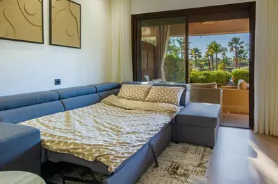a blue couch in a living room with a bed at Marrakech golf Prestigia Jade in Marrakech