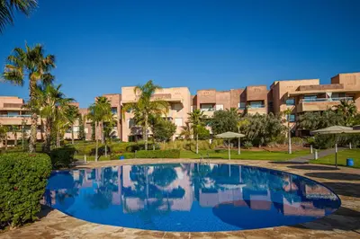 a swimming pool in front of a large building at Marrakech golf Prestigia Jade in Marrakech