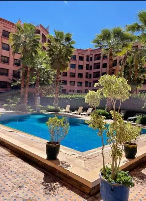 a swimming pool with palm trees and a building at Hivernage Marrakech in Marrakech