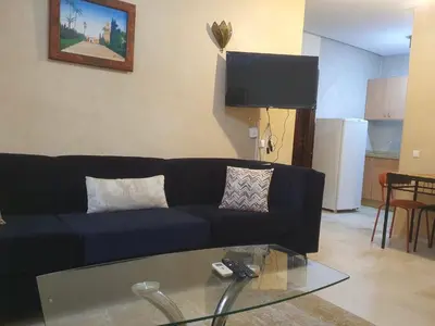 a living room with a blue couch and a glass table at Hivernage Marrakech in Marrakech