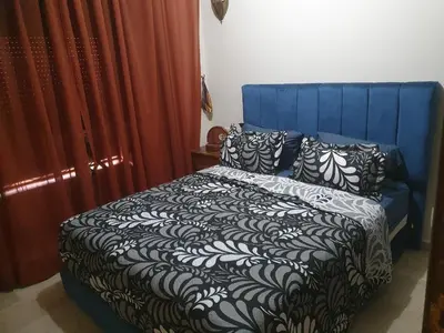 a blue bed with black and white sheets and pillows at Hivernage Marrakech in Marrakech