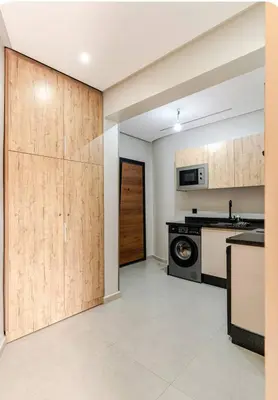 a kitchen with wooden cabinets and a washer and dryer at Studio Nahellan in Marrakech