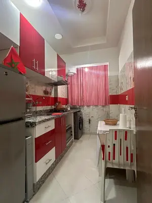 a kitchen with red cabinets and a table in it at Aljawhara 2BD in Marrakech
