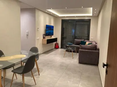 a living room with a couch and a table and chairs at Perfect condo for tourists in semlalia in Marrakech