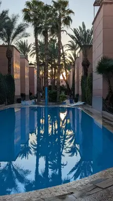 a swimming pool with palm trees in a resort at Riad absar in Marrakech
