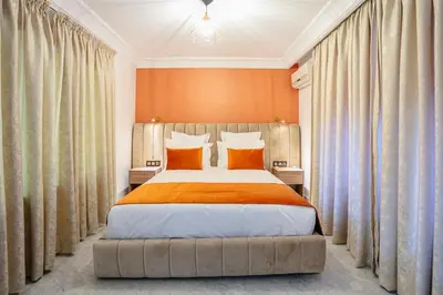 a bedroom with a large bed with orange walls and curtains at Pause in the City - Duplex - Marrakech Centre in Marrakech