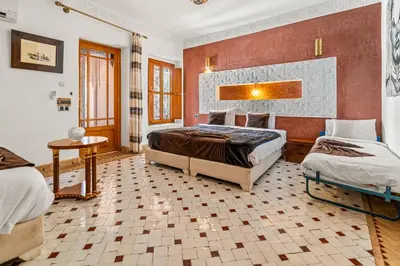 a large bedroom with two beds and a table at Palais Nejma - Locanda Boutique Collection in Marrakech