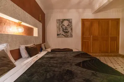 a bedroom with a large bed and a wooden cabinet at Palais Nejma - Locanda Boutique Collection in Marrakech