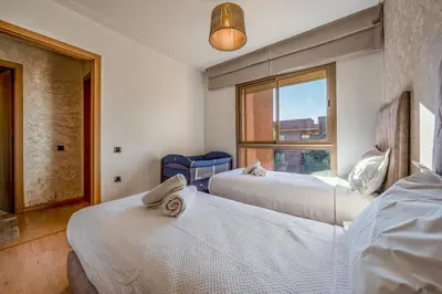 two beds in a room with a window at Prestigia Opale - Superb condo with Golf & Pool views in Marrakech