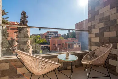 a patio with two chairs and a table on a balcony at Appartement Romantique et Moderne a Gueliz in Marrakech
