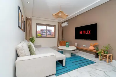 a living room with a couch and a tv on a wall at Appartement Romantique et Moderne a Gueliz in Marrakech