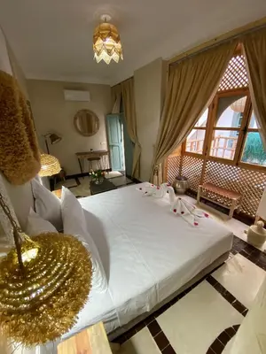a bedroom with a large white bed with a chandelier at Riad Fontaine Arabe Privatisation in Marrakech