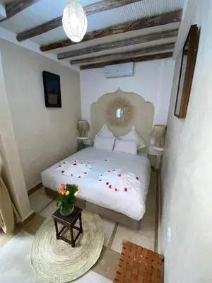 a bedroom with a bed and a table with flowers on it at Riad Fontaine Arabe Privatisation in Marrakech