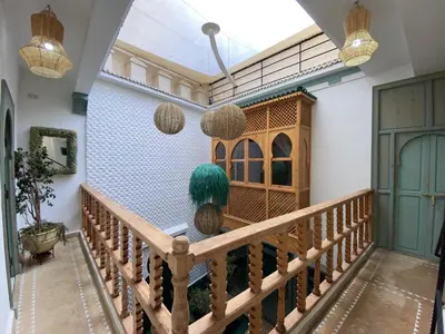 a hallway with a wooden railing and a staircase with hanging lights at Riad Fontaine Arabe Privatisation in Marrakech