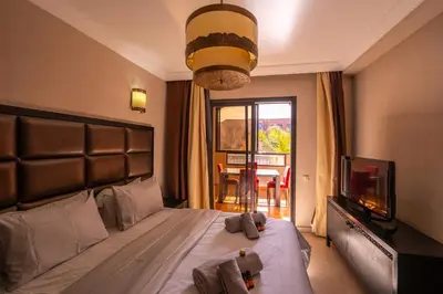 a bedroom with a bed and a tv and a window at River Palm élégant appartement 2 ch vue piscine in Marrakech