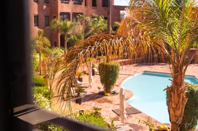 a view of a swimming pool with a palm tree at River Palm élégant appartement 2 ch vue piscine in Marrakech