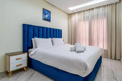 a bedroom with a large bed with a blue headboard at Stylish Flat, Aube hivernage Fibre-Pool & Parking in Oulad Akkou