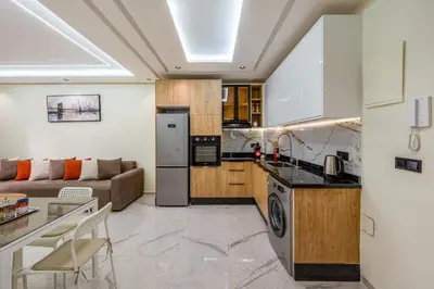 a kitchen and a living room with a couch at Stylish Flat, Aube hivernage Fibre-Pool & Parking in Oulad Akkou