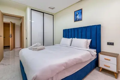a bedroom with a large bed with a blue headboard at Stylish Flat, Aube hivernage Fibre-Pool & Parking in Oulad Akkou