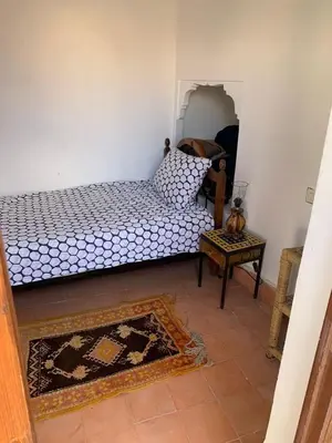 a bedroom with a bed and a table with a rug at Riad Zinnha 2 in Marrakech