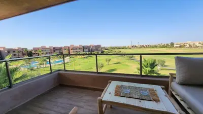 a balcony with a couch and a view of a golf course at Appartement avec GOLF PISCINE Prestigia Jade in Marrakech