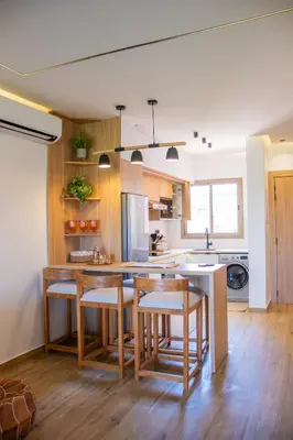 a kitchen with wooden cabinets and a kitchen island with stools at Appartement avec GOLF PISCINE Prestigia Jade in Marrakech