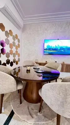 a living room with a table and chairs and a tv at Bel appartement à Babylone 1 in Marrakech