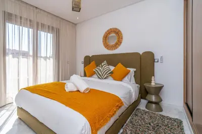 a bedroom with a large bed with an orange blanket at Urban Escape in Gueliz with Balcony and Wifi in Marrakech